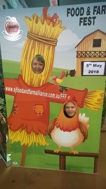 Perth Royal Show volunteers with head in a photoboard showing a scarecrow and a chicken.