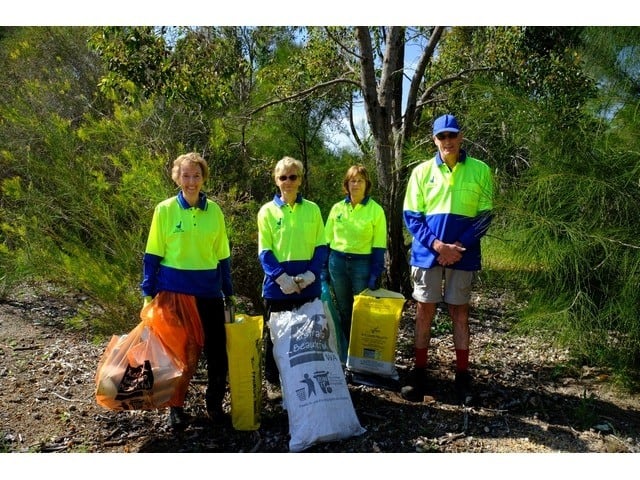 four members of Byford Enviro-link with bags of rubbish and plants guards at Mundijong Road
