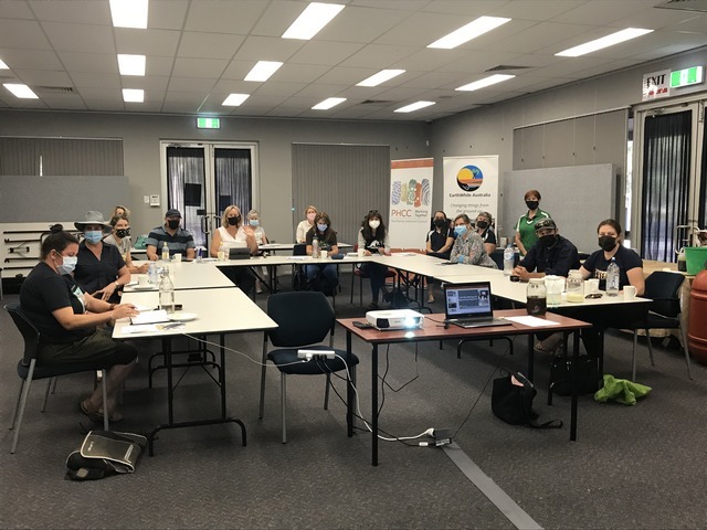 people sitting behind desks and wearing masks at a workshop