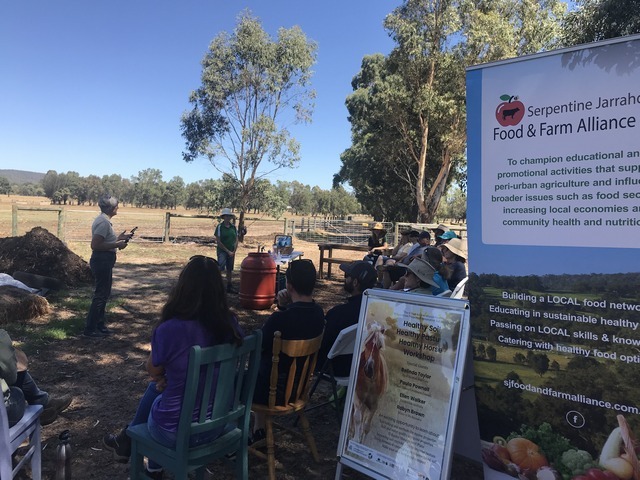 people sitting in a paddock listening to someone speaking