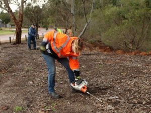 2 people bending over in urban bushland