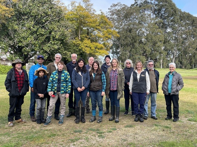 several men and woman posing for a photo in a bush setting