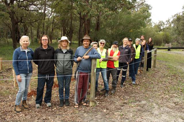a group of adult volunteers standing by a rura fence