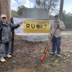 two men standing in front of an RUOK banner